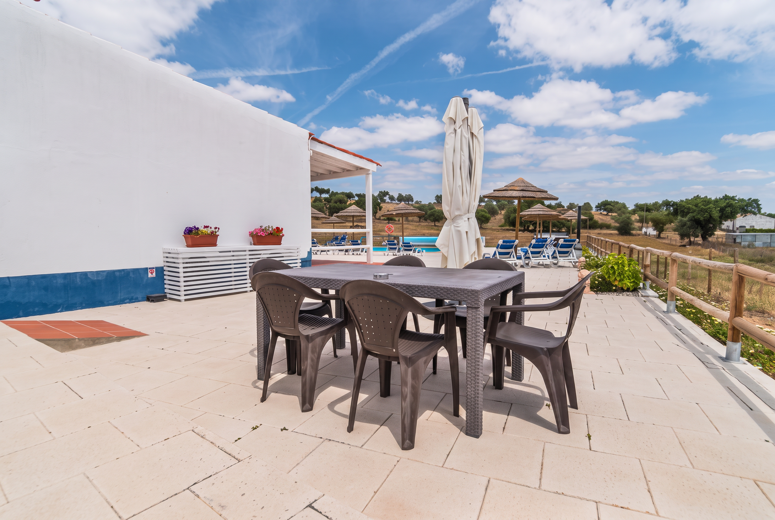 Pátio com mesa e cadeiras junto à piscina